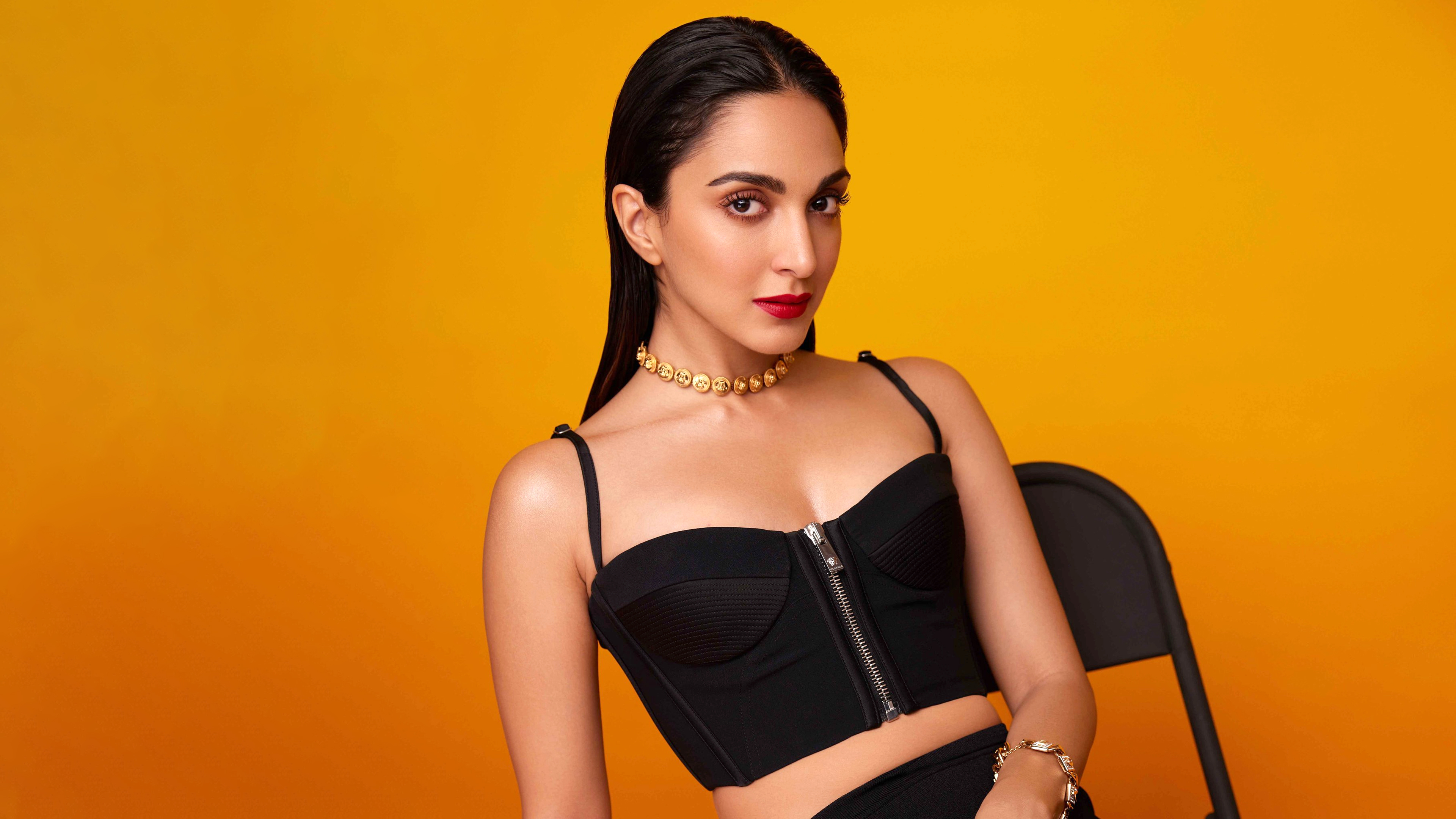 Kiara Advani, schwarzes Kleid, oranger Hintergrund, indische Schauspielerin